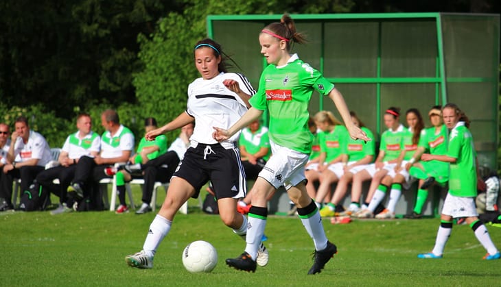 Girls fighting for a white soccer ball on a green field in Dusseldorf, Germany