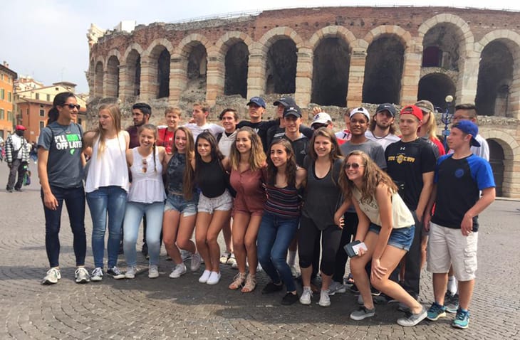 Girls and Boys soccer team from Pennsylvania standing in front of an arched stadium in Italy