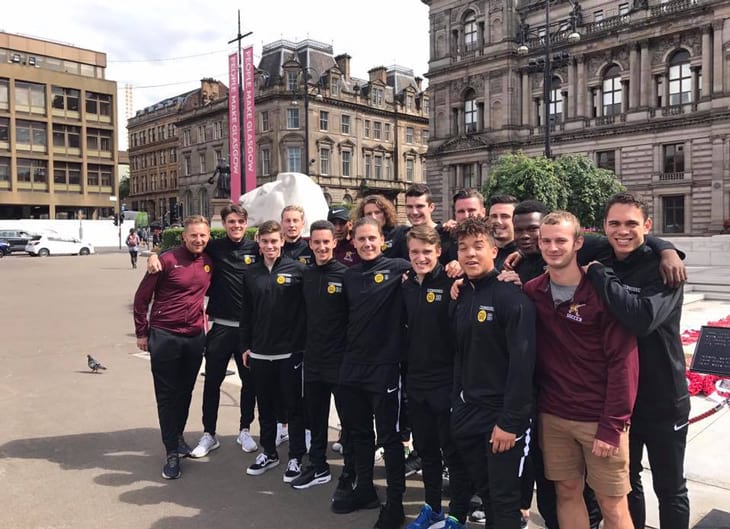 Row of Gannon University Men's soccer team standing in front of Stone buildings in Glasgow, England.